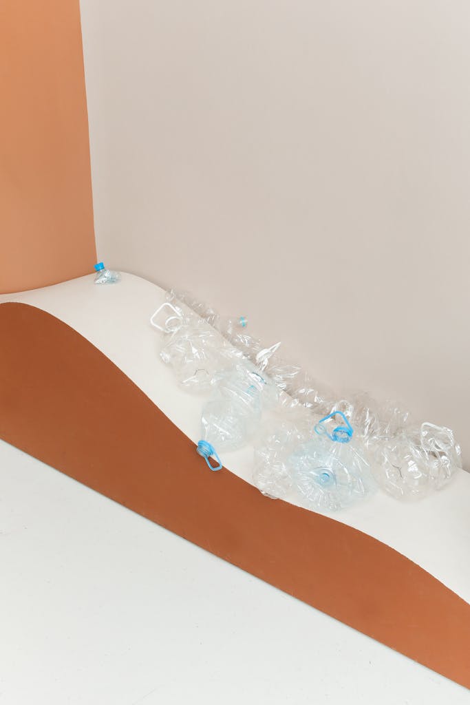 Artistic still life of crumpled plastic bottles on a modern, colored backdrop highlighting waste.